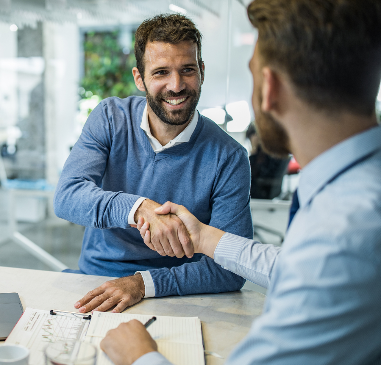 Two men shaking hands at a table
