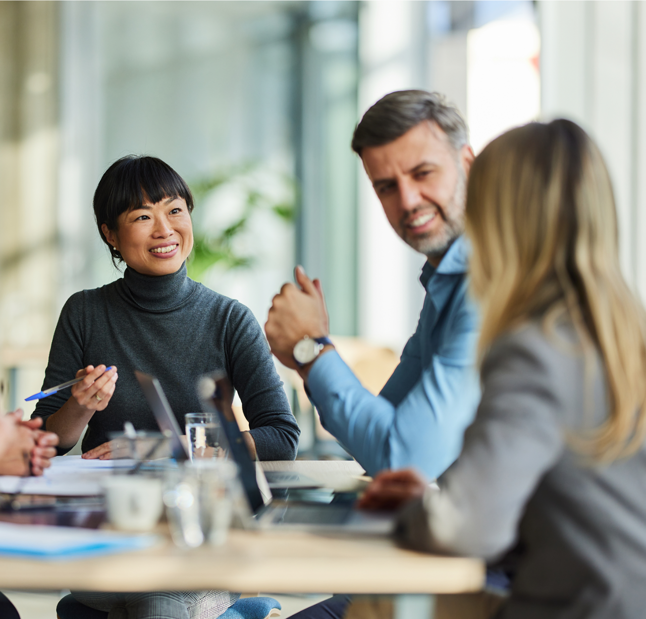 Two women and a man sitting around a table having a meeting