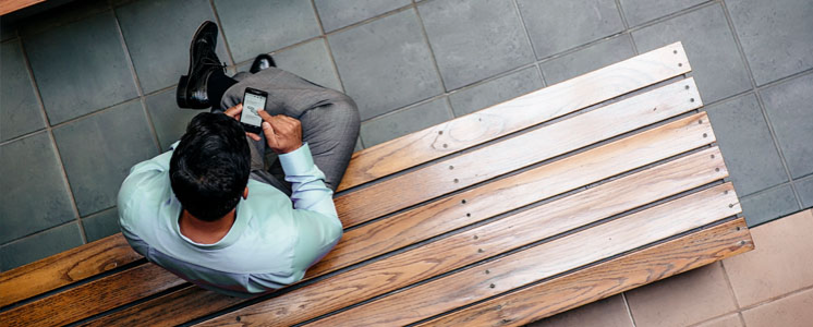 a man sitting on a bench, scrolling his phone