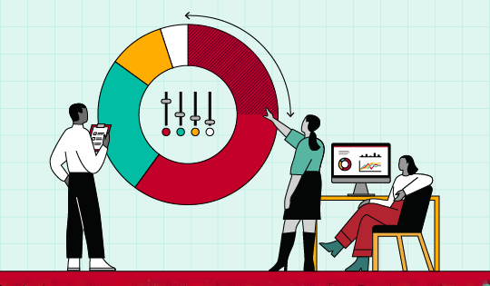 Three people collaborating in a meeting, representing Vanguard’s Strategic Asset Allocation Committee. One is holding a clipboard as another points toward a pie chart with controls in the center. The third person is sitting in front of a computer screen watching the discussion. 