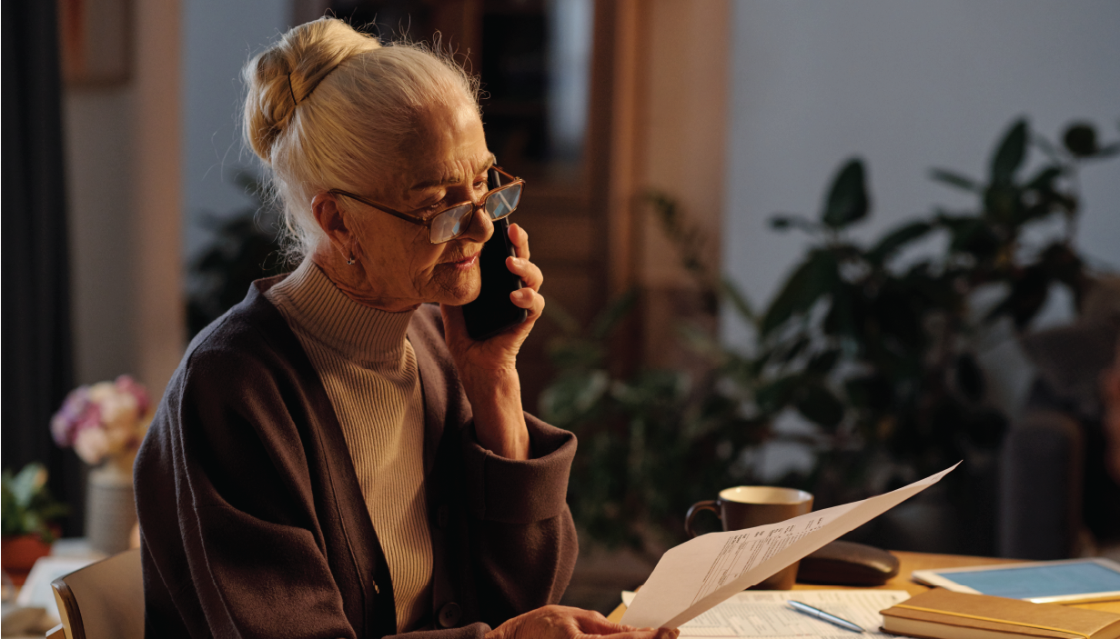 A person holds a cellphone in one hand and a document in the other.