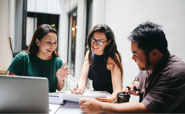 A man and two women sitting around a table, having a meeting.